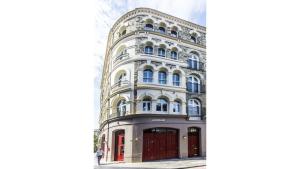 Pass the Keys Spacious Luxury Apartment in the Heart of London في لندن: مبنى أبيض كبير بأبواب حمراء على شارع
