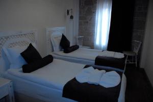 two white beds with black pillows in a room at Orchis Hotel in Ayvalık