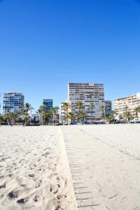 アリカンテにあるSan Juan Beach apartment with AC and viewsの背景に高い建物が立ち並ぶ砂浜