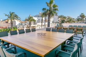 un grande tavolo in legno e sedie su un patio con palme di Villa Mar 18 a Can Picafort