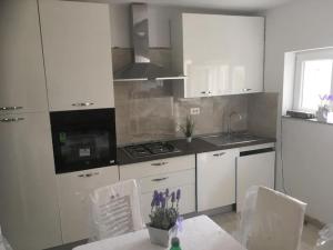 a kitchen with white appliances and a table and chairs at Apartman Milica in Vrgada