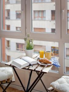 a table with a plate of food and two cups of orange juice at 115A - Amplia vivienda en Playa San Lorenzo in Gijón