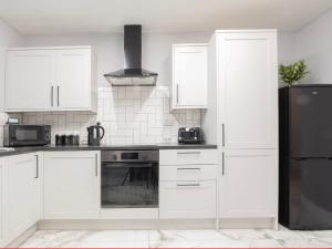 a kitchen with white cabinets and a black refrigerator at Pass the Keys Spacious house with free parking in Doncaster