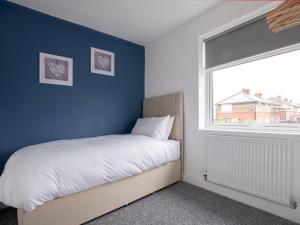 1 dormitorio con 1 cama con pared azul en Pass the Keys Spacious house with free parking, en Doncaster