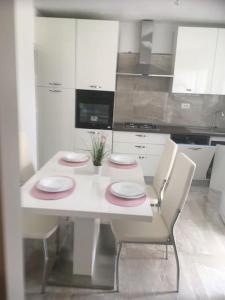 a white kitchen with a white table and chairs at Apartman Milica in Vrgada