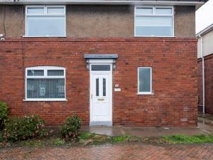 een rood bakstenen huis met een witte deur bij Pass the Keys Spacious house with free parking in Doncaster