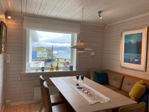 a dining room with a table and a window at Nyksund House Kapellbakken 3 bedrooms with sea view in Nyksund