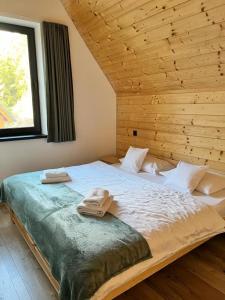 1 dormitorio con 1 cama grande y pared de madera en Chata Demian, en Demänovská Dolina
