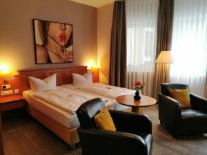 a hotel room with a bed and two chairs at Hotel Alexa in Bad Mergentheim