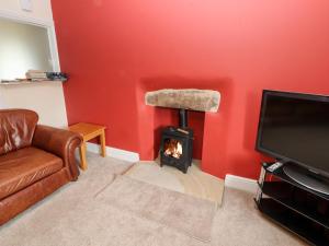 a living room with a fireplace with a couch and a tv at Cobbleken in Cockermouth