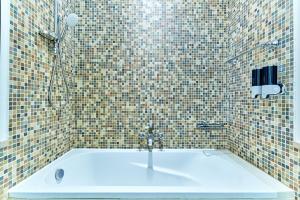 a bathroom with a bath tub with a shower at Golden Homes 1BR Reehan miniPalais Beside Burjh & Dubai mall Downtown in Dubai +9 photos