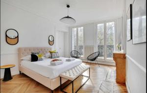 a white bedroom with a large bed and windows at Residence Le Marais by Studio prestige in Paris