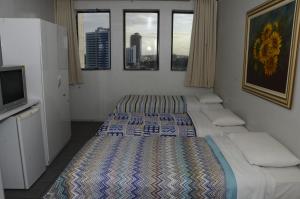 a bedroom with two beds and a tv and windows at Titão Plaza Hotel in Campina Grande