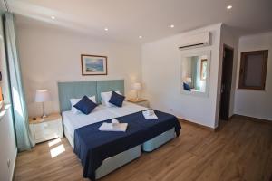 a bedroom with a bed with blue sheets and blue pillows at Casa da Ladeira Branca in Lagos