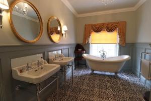 a bathroom with two sinks and two mirrors at The Georgian Swansea in Swansea
