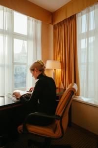 uma mulher sentada numa secretária num quarto de hotel em Ghent Marriott Hotel em Gent