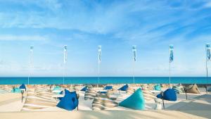 a sandy beach with blue chairs and the ocean at Radisson Resort & Spa Hua Hin in Cha Am
