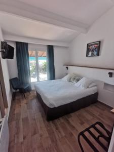 a bedroom with a bed and a chair and a window at L'auberge Camarguaise in Saintes-Maries-de-la-Mer