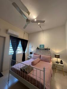 Schlafzimmer mit einem Bett mit rosa Kissen und einem Deckenventilator in der Unterkunft Eira Homestay Lost World Of Tambun M uslim only in Ipoh