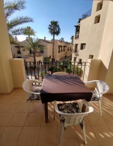 una mesa y sillas en un balcón con palmeras en Apartamento 3 dormitorios Roda Golf, en Murcia