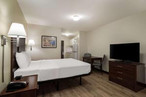 a hotel room with a bed and a flat screen tv at Suburban Studios Denver Central-Arvada in Arvada