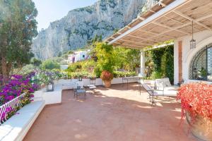 an outdoor patio with tables and chairs and flowers at Villa Le Tuie by Elite Villas in Capri
