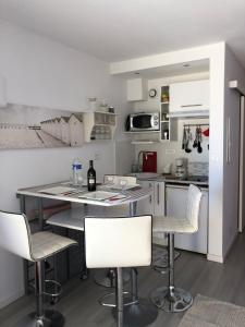 kuchnia z białymi krzesłami i blatem w obiekcie Charmant studio à Cros de Cagnes w Cagnes-sur-Mer