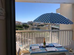 stolik z butelką wina i parasol na balkonie w obiekcie Charmant studio à Cros de Cagnes w Cagnes-sur-Mer