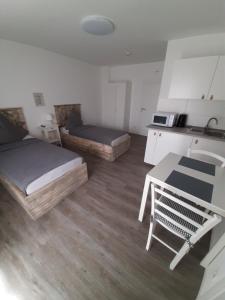a room with two beds and a table and a kitchen at Pension Asche in Münster