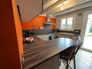 a kitchen with orange walls and a wooden counter top at *La douce étape des Châteaux * in Bracieux