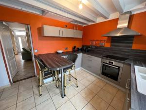 a kitchen with a wooden table and an orange wall at *La douce étape des Châteaux * in Bracieux