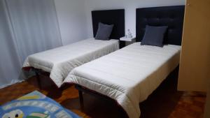 2 Betten mit weißer Bettwäsche und blauen Kissen in einem Zimmer in der Unterkunft Apartamento Mar Azul in Vila Nova de Cerveira