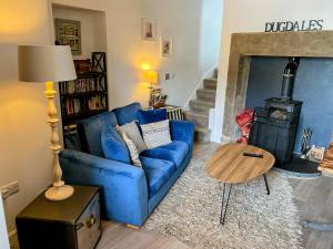 un sofá azul en una sala de estar con chimenea en Dugdales Cottage en Settle