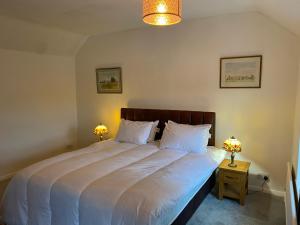 a bedroom with a large white bed with two lamps at Jasmine Cottage in Bakewell