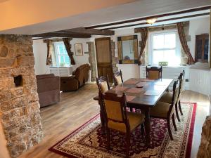 a dining room with a table and a stone fireplace at Jasmine Cottage in Bakewell