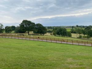 a fence in a field with green grass and trees at Jasmine Cottage in Bakewell