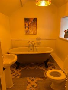 a bathroom with a tub and a toilet at Jasmine Cottage in Bakewell +5 photos