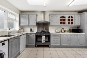 una cucina con armadi bianchi e piano cottura di luxury 6 bedroom house in Aylesbury, Free parking a Buckinghamshire