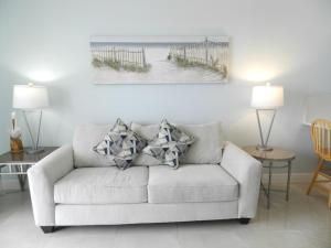 a living room with a white couch with pillows at 1 BR Resort Condo Direct Oceanfront Wyndham Ocean Walk - Daytona Funland 1307 in Daytona Beach