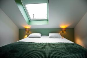 a bedroom with a bed with two pillows and a window at City Housing Genk in Genk