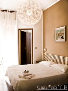 a bedroom with a large bed and a chandelier at Hotel Ariston in Cesenatico
