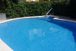 une grande piscine bleue avec un panneau. dans l'établissement Casa adosada con piscina comunitaria Solo familias no grupos de jovenes, à Salou