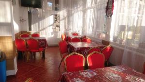 a restaurant with red chairs and tables and windows at vila strugurelu hostel in Predeal