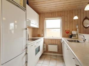 a kitchen with a white refrigerator and a sink at Holiday Home Dolma - 75m from the sea in NW Jutland by Interhome in Løkken