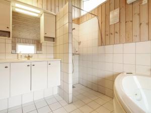 a bathroom with a shower and a sink and a tub at Holiday Home Dolma - 75m from the sea in NW Jutland by Interhome in Løkken