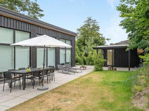 a patio with a table and chairs and an umbrella at Holiday Home Ebke - 70m from the sea in Sealand by Interhome in Gilleleje