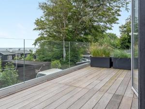 a balcony with a wooden floor and glass walls at Holiday Home Ebke - 70m from the sea in Sealand by Interhome in Gilleleje