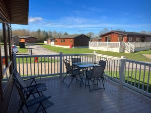 a patio with a table and chairs on a deck at Tulip Lodge with Hot Tub in Malton