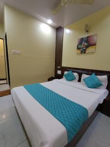 a bedroom with a large white bed with blue pillows at Hotel Amber-colaba in Mumbai