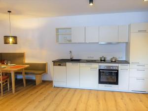 cocina con armarios blancos, mesa y comedor en Apartment Freiheit-La by Interhome en Schnann